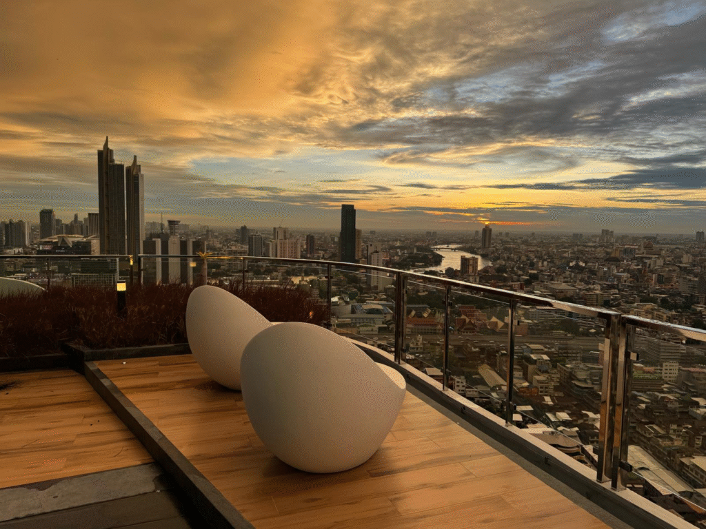 Bangkok skyline from the top of a building with chairs looking out.